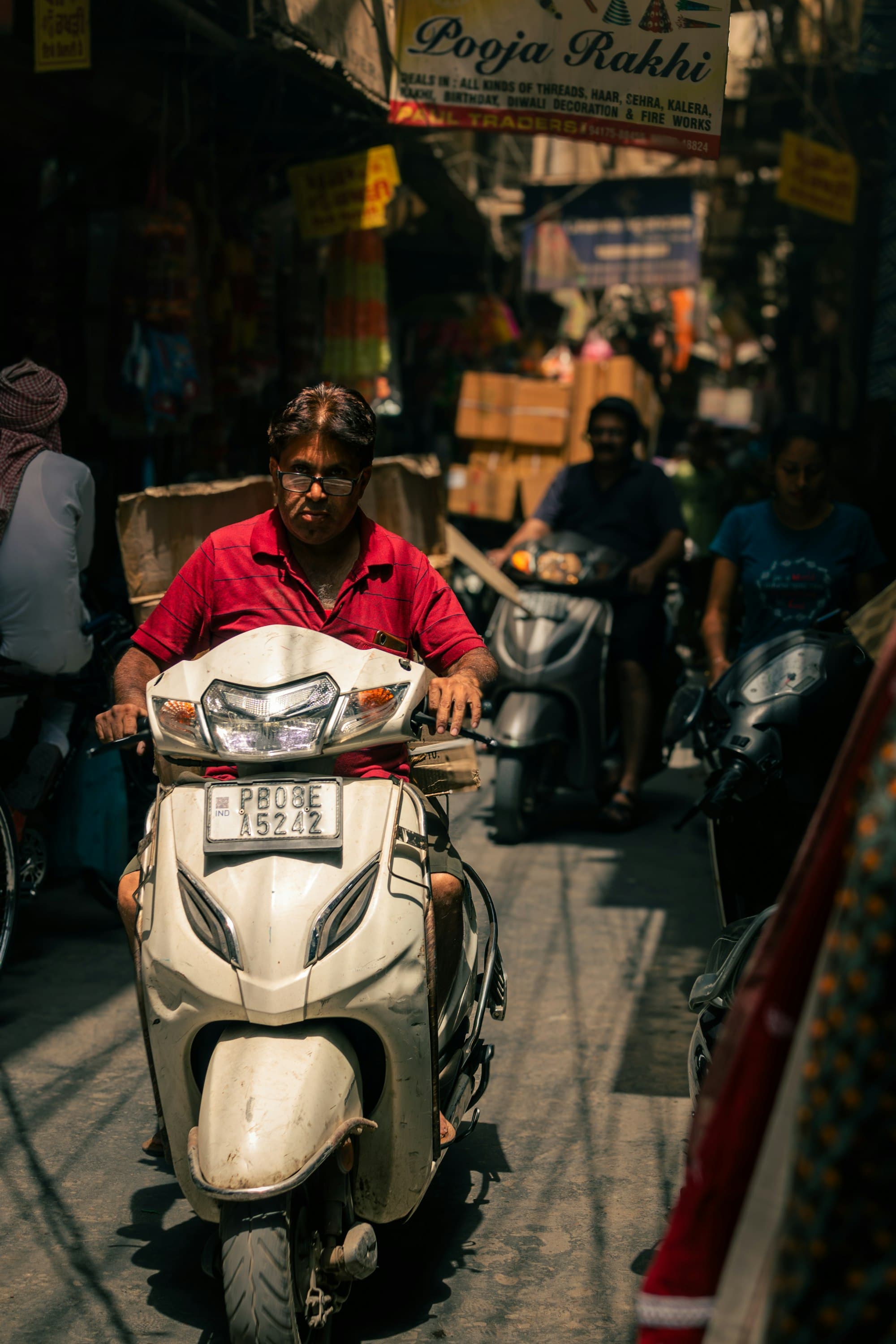 Rider on a white scooter in a market lane