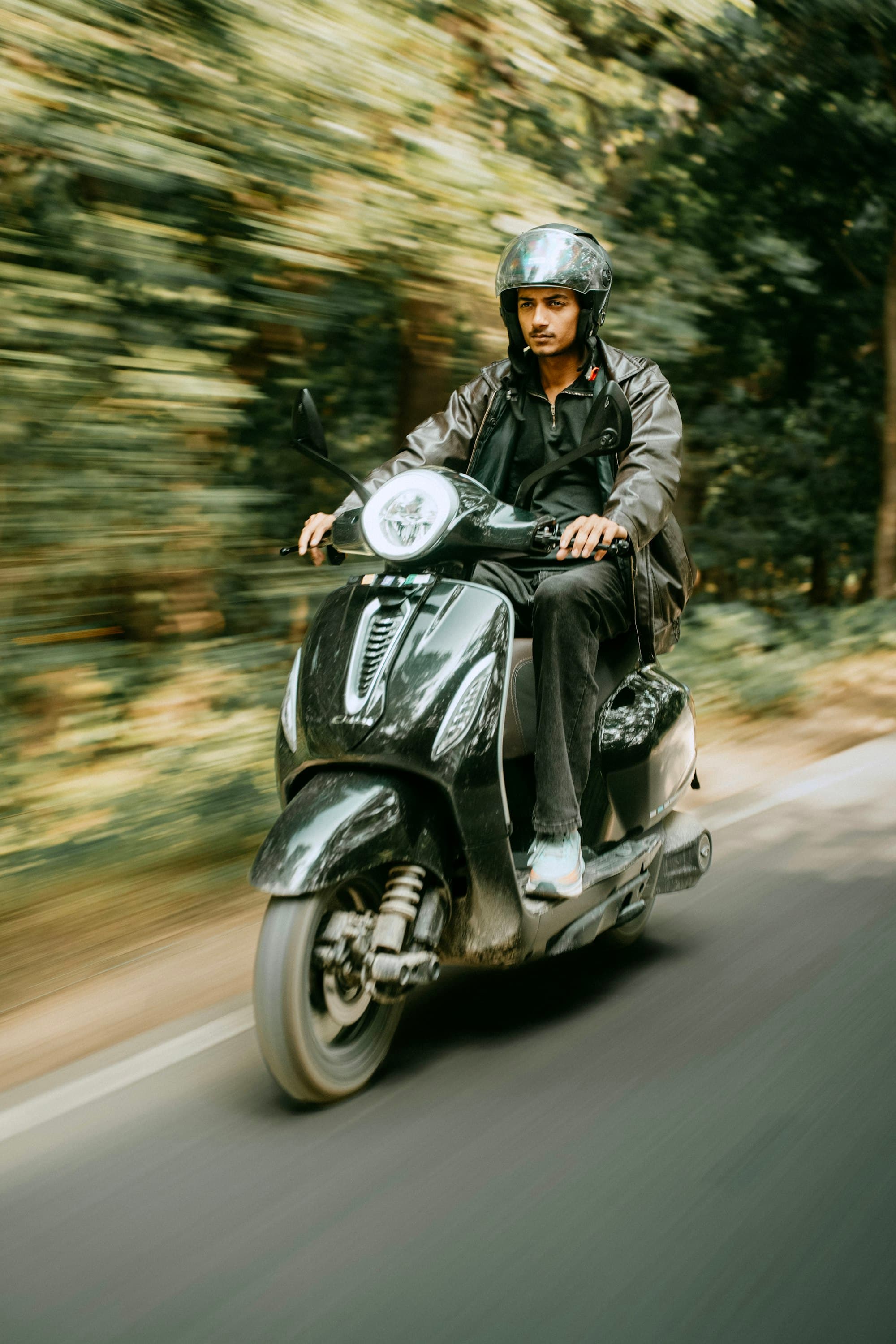 Rider on a scooter on a tree-lined road
